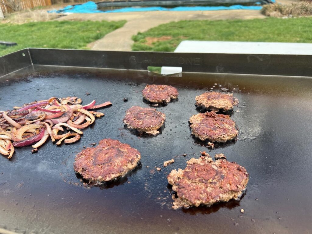 Smash burger patties flipped, seared side up, on the griddle