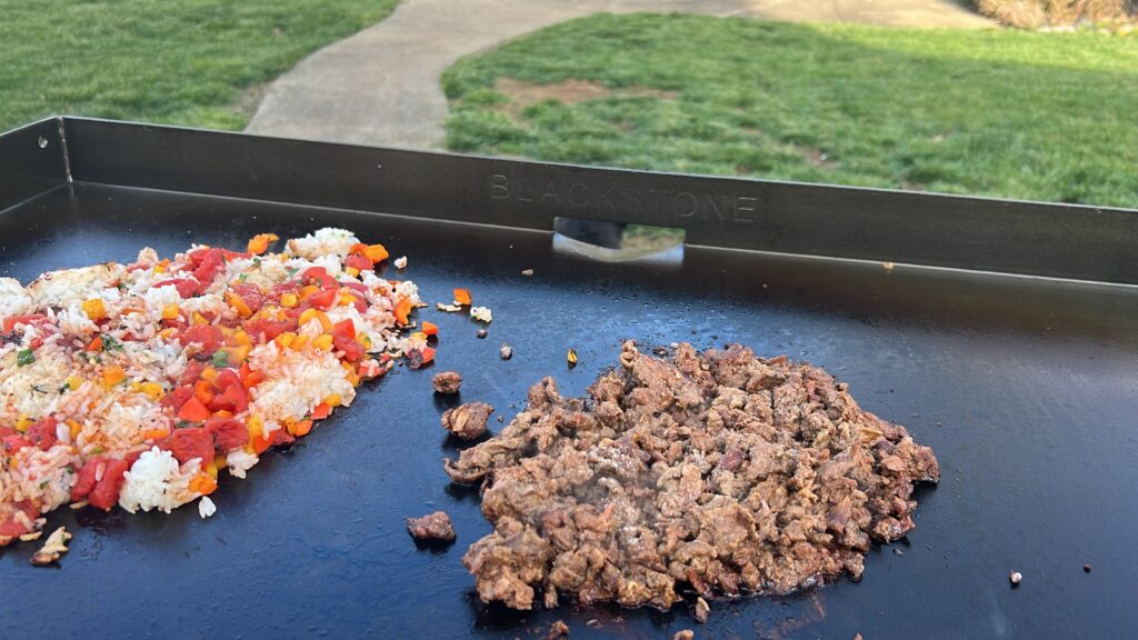 Rice and veggies next to browning shredded beef on the griddle