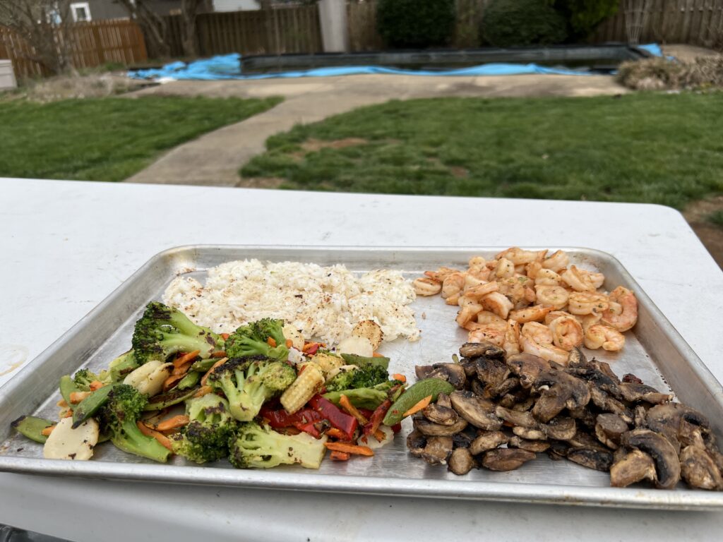 A finished plate of rice, stir-fry vegetables, shrimp, and mushrooms