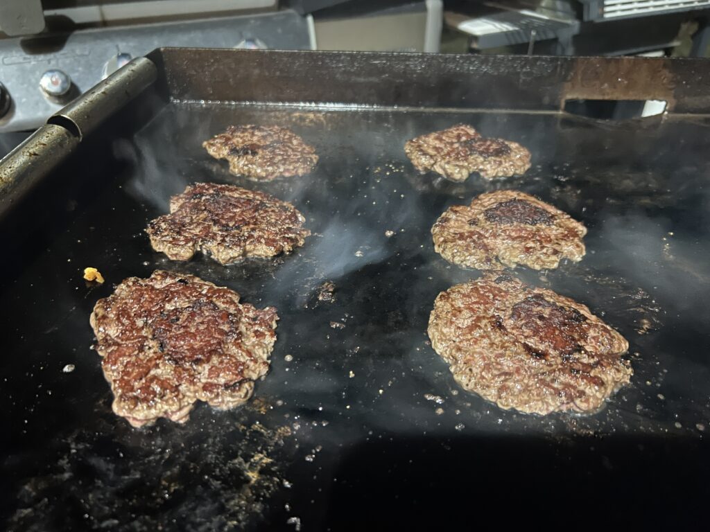 Smashed beef patties building a crust on the griddle