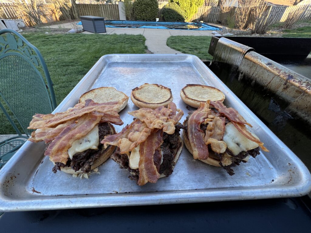 Finished beef smash burgers piled high with crispy bacon