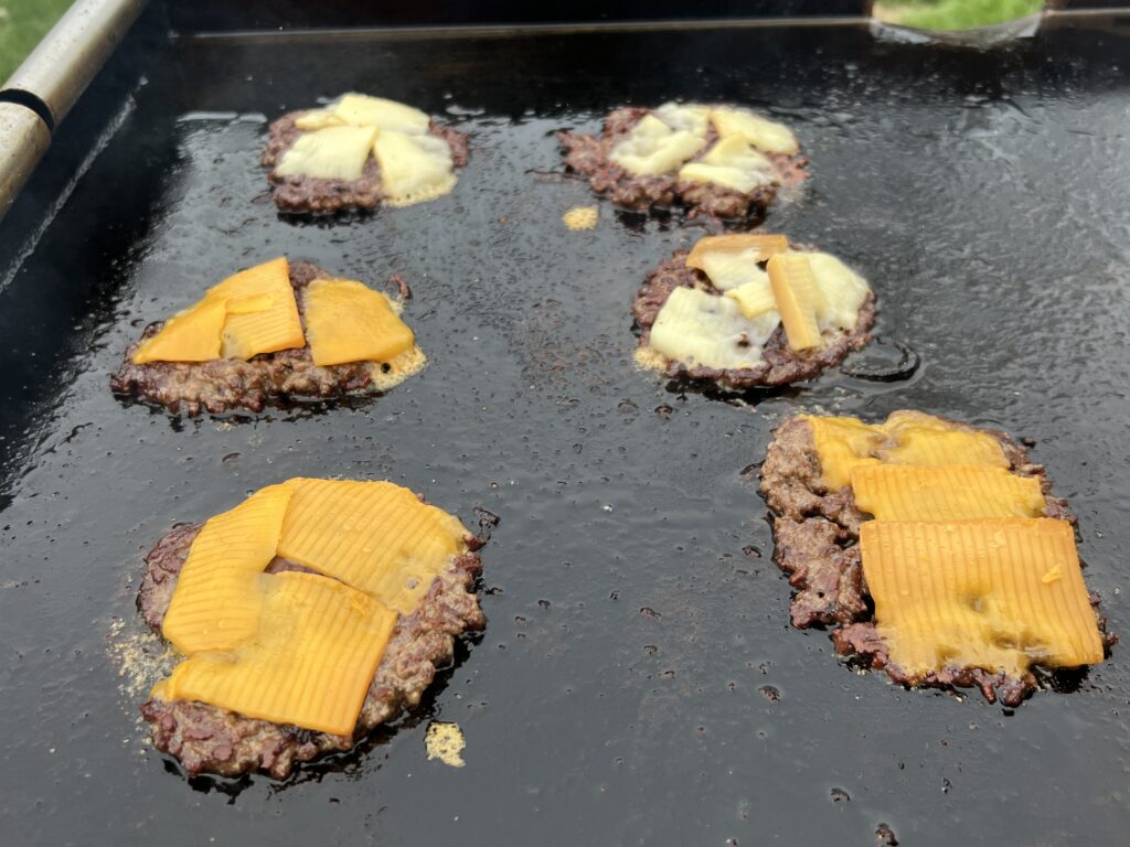 Beef smash burger patties with a mix of white and sharp cheddar melting on top