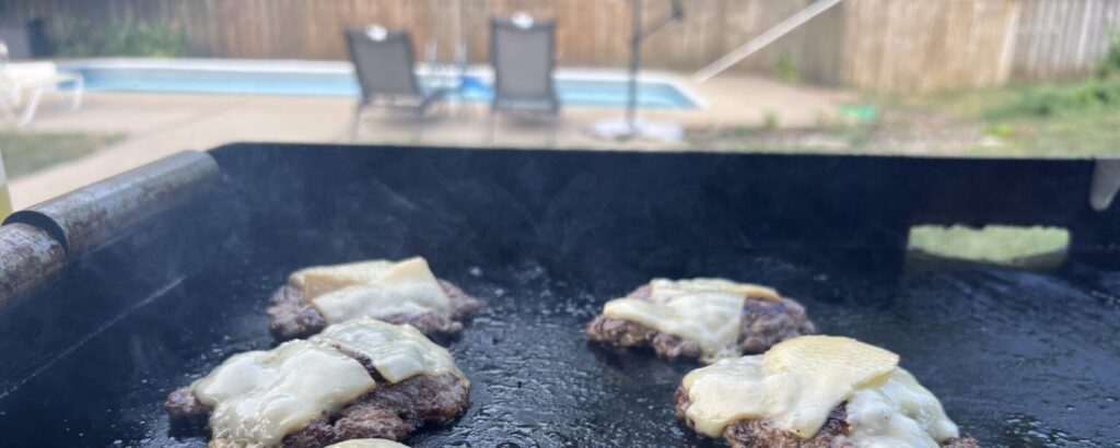 Close-up of pork smash burger patties with cheese melting into the crust